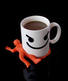 Silicon drink coaster shaped like orange splat character under a white mug
