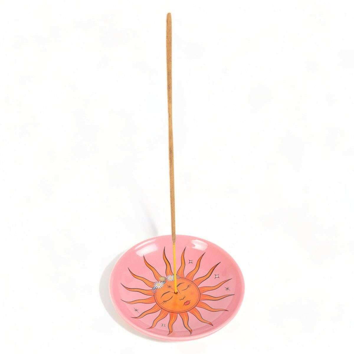 Pink sun incense holder with vertical incense stick and smiling sun artwork