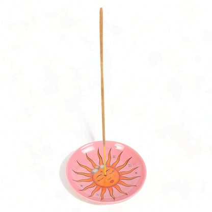 Pink sun incense holder with vertical incense stick and smiling sun artwork