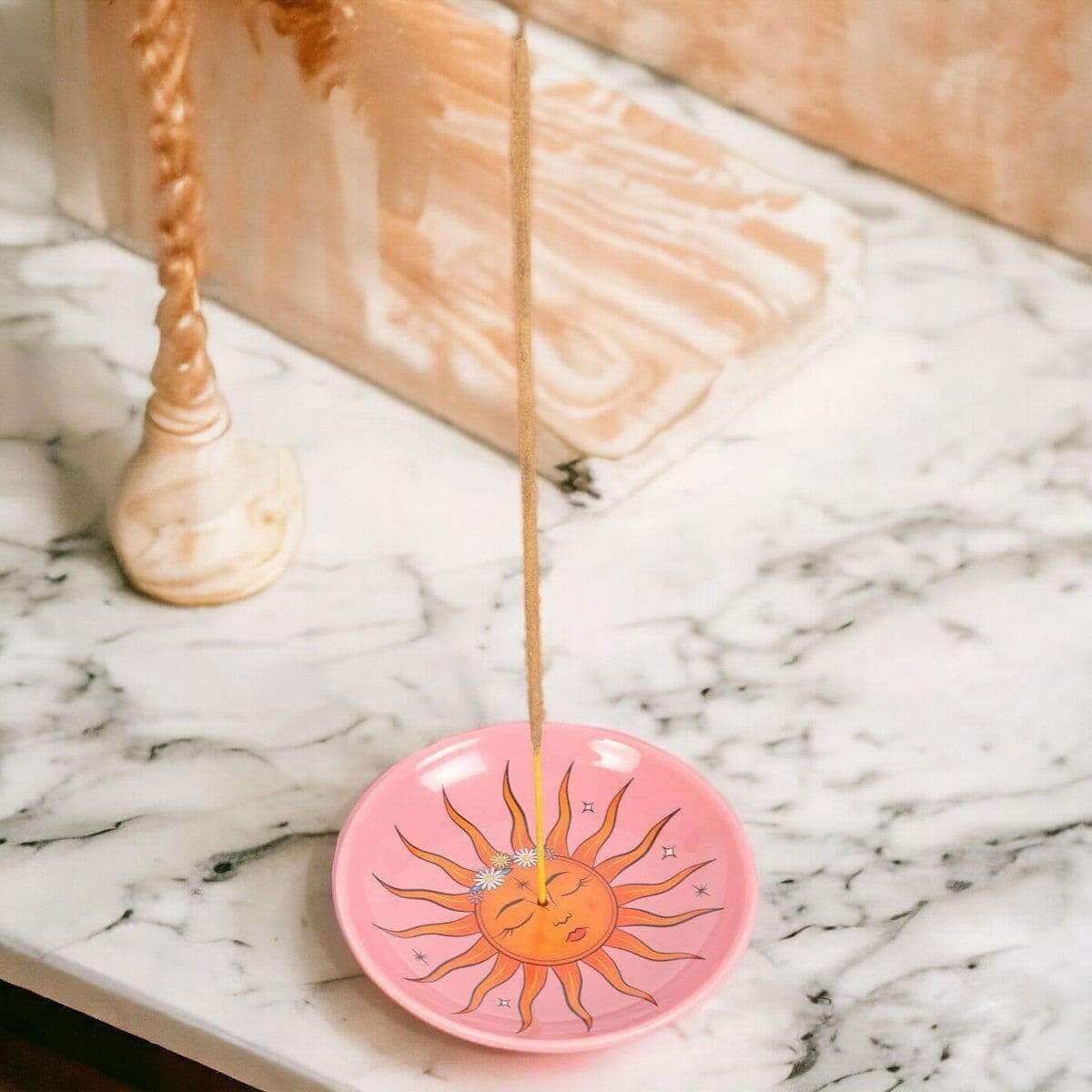 Pink sun incense holder with incense stick inserted through center