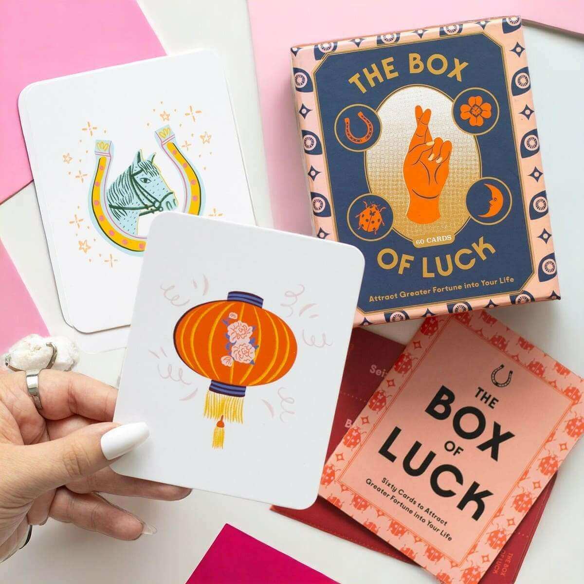 Tarot card box with a hand holding an illustrated card and other cards nearby