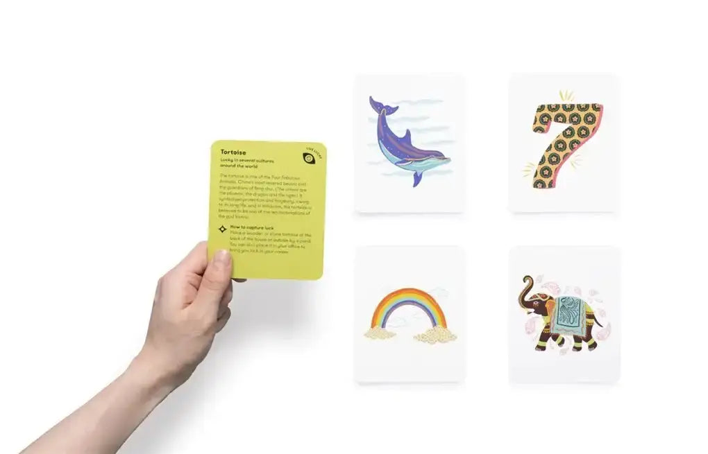 Hand holding a green tarot card with other cards showing animal and rainbow icons