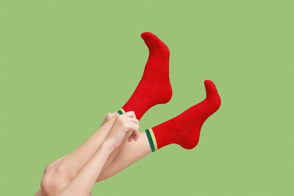 Watermelon socks, red with seed speckles and green-striped cuffs, held in hands