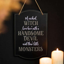 Black hanging sign with white witch lettering and top loop rope