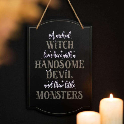 Black hanging sign with white witch lettering and top loop rope